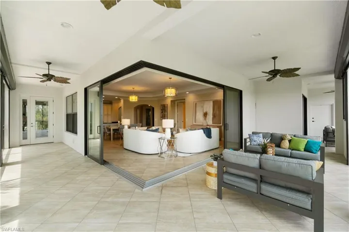 Living room featuring ceiling fan, arched walkways, light tile patterned flooring, and ornamental molding