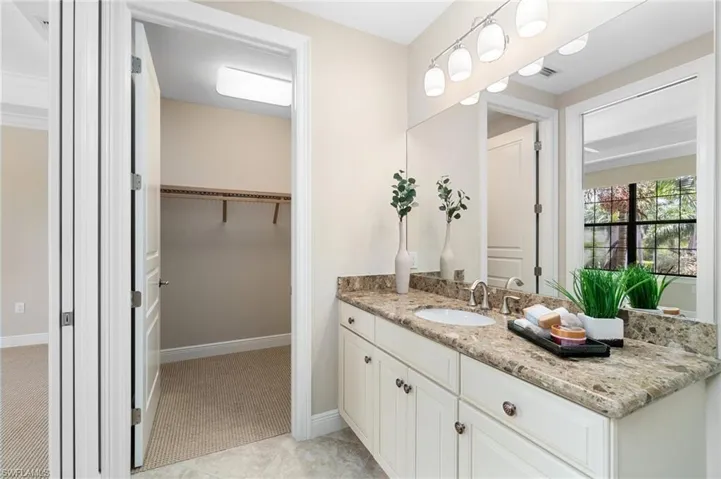 Bathroom featuring vanity, a spacious closet, and baseboards