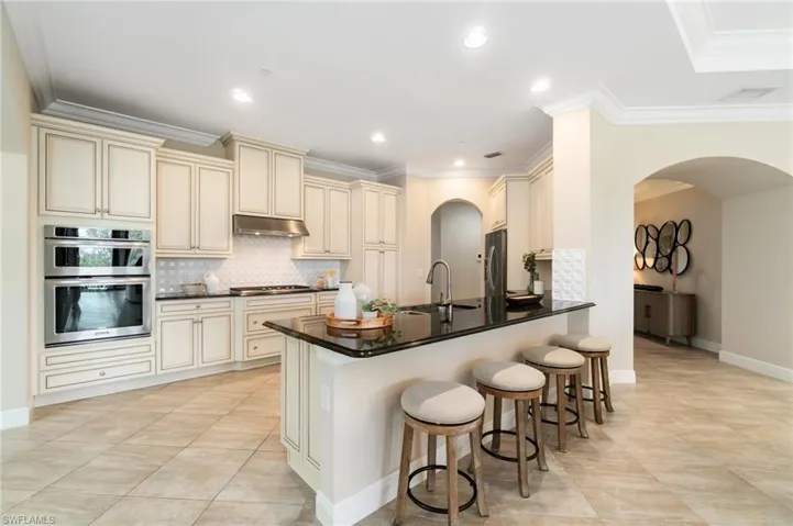 Kitchen with cream cabinets, a sink, appliances with stainless steel finishes, a peninsula, and ornamental molding