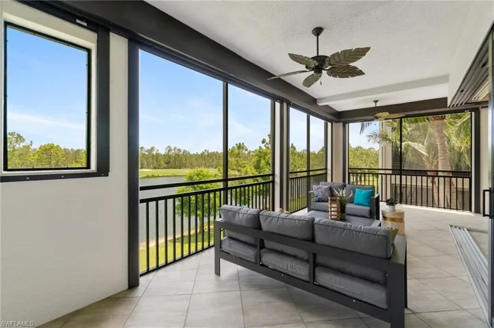 Sunroom / solarium with a water view, an outdoor living space, ceiling fan, and view of scattered trees