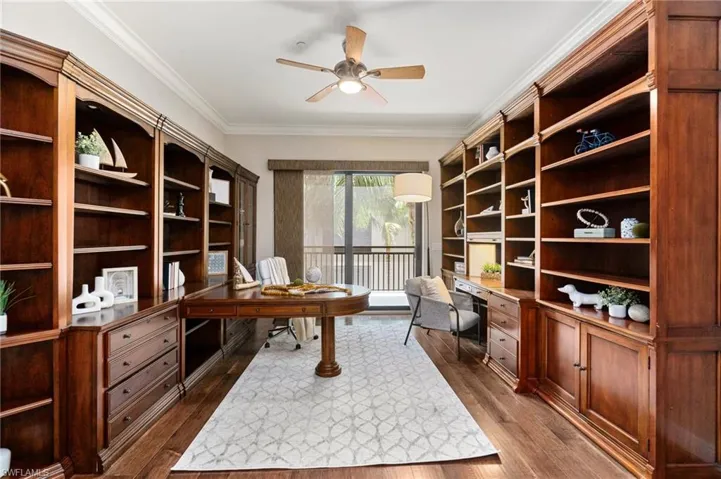 Home office featuring built in study area, a ceiling fan, ornamental molding, and dark wood-style flooring