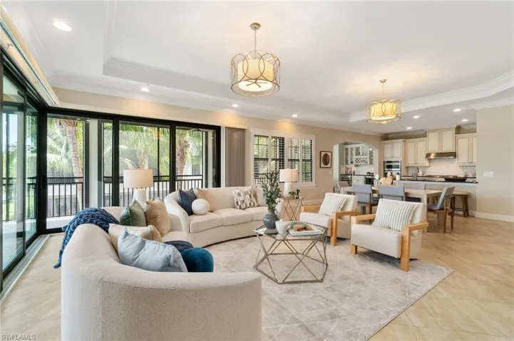 Living room with a raised ceiling, recessed lighting, and crown molding