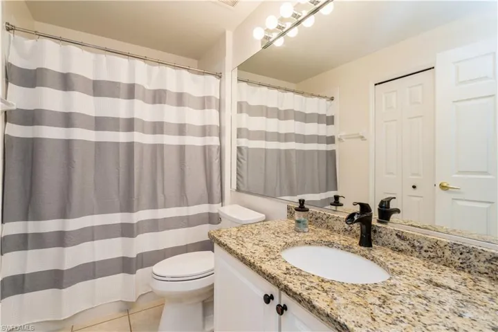 Full bathroom featuring toilet, vanity, tile patterned floors, and a shower with curtain