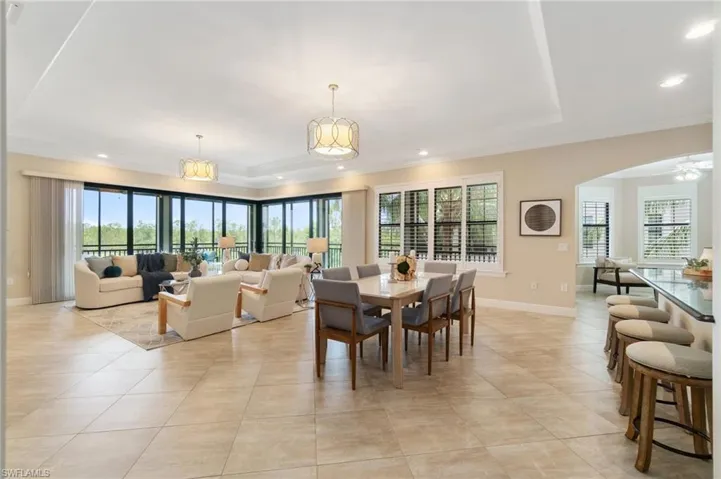Dining area featuring plenty of natural light, ornamental molding, arched walkways, light tile patterned flooring, and baseboards