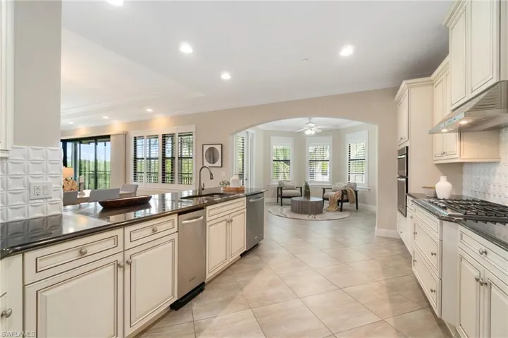 Kitchen featuring a sink, stainless steel appliances, cream cabinets, open floor plan, and crown molding