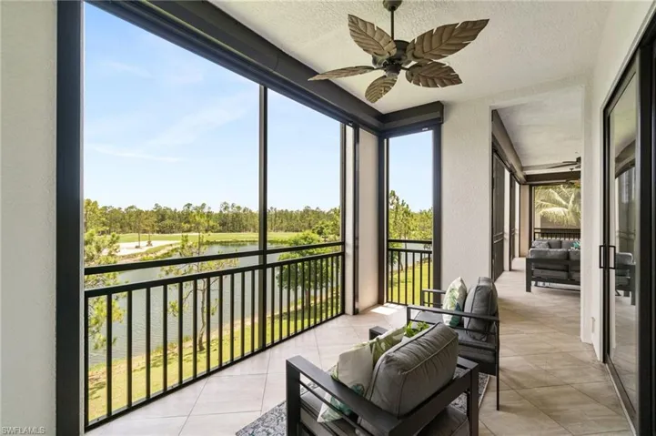 Sunroom / solarium featuring a ceiling fan, a water view, view of wooded area, and an outdoor hangout area