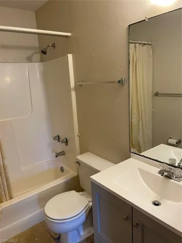 Full bathroom with vanity, shower / bath combo, and toilet
