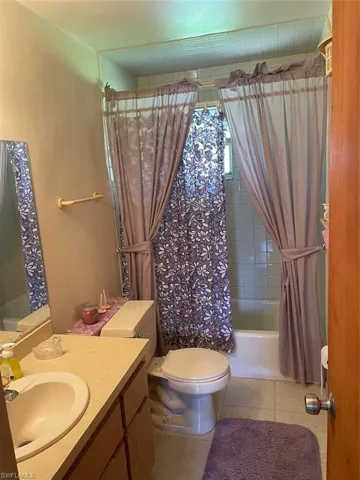 Full bathroom featuring vanity, toilet, shower / bathtub combination with curtain, and tile patterned floors