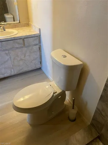 Bathroom with hardwood / wood-style flooring, toilet, and vanity