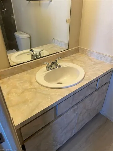 Bathroom with hardwood / wood-style flooring, toilet, and vanity
