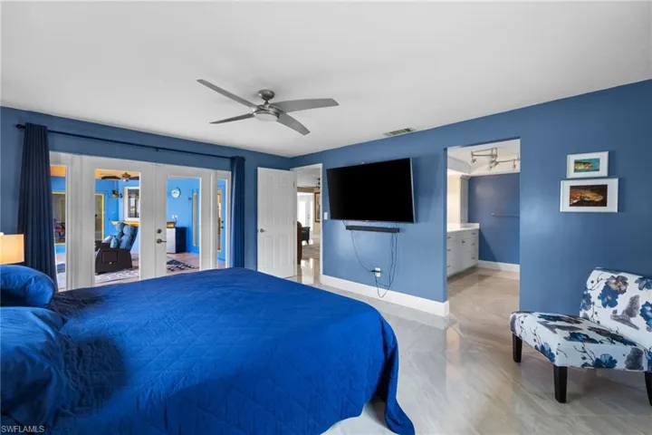 Bedroom featuring french doors, visible vents, a ceiling fan, ensuite bath, and baseboards