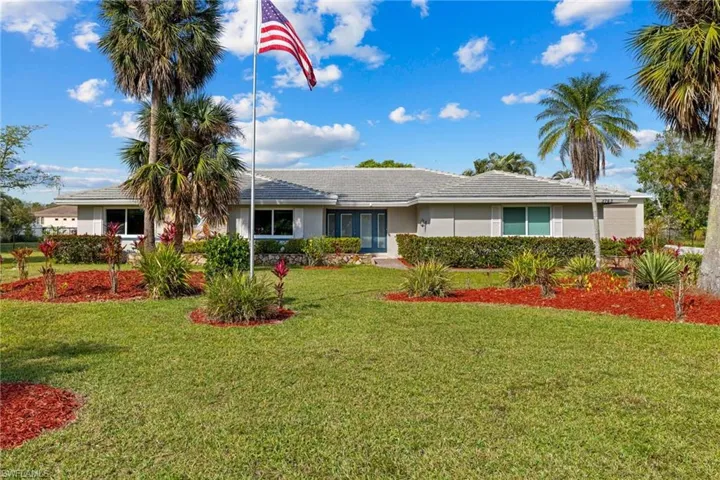 Ranch-style home with a tile roof, a front lawn, and stucco siding