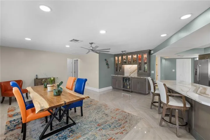Dining space featuring baseboards, visible vents, wine cooler, indoor wet bar, and recessed lighting