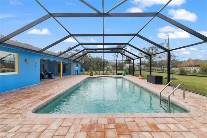 Outdoor pool featuring a yard, glass enclosure, and a patio