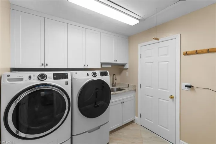 Washroom with cabinet space, attic access, a sink, and independent washer and dryer