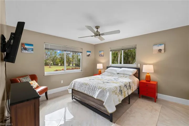 Bedroom with ceiling fan, multiple windows, and baseboards