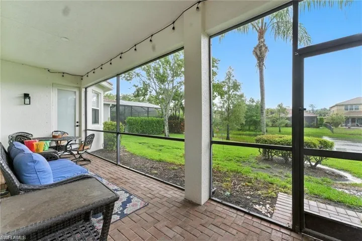 SCREENED-IN LANAI WITH VIEW OF LAKE AND PALM TREES. DOOR SEEN IN PICTURE IS THE PRIMARY BEDROOM ENTRANCE