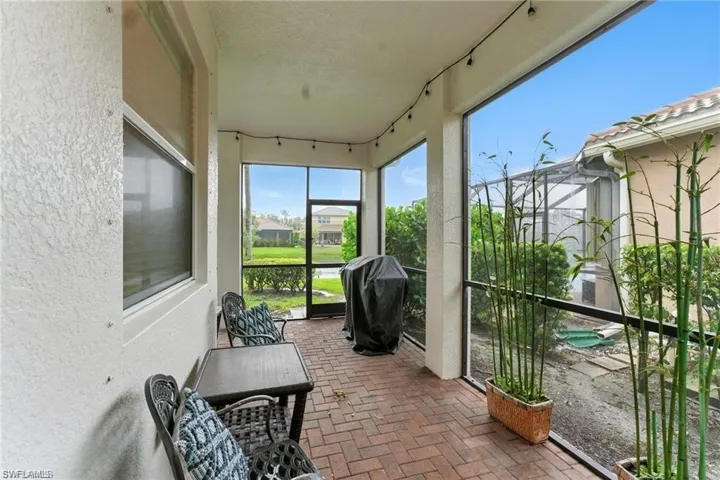 SCREENED-IN LANAI IS L SHAPED AND HAS TWO SITTING AREAS, GRILL, AND PLANTS