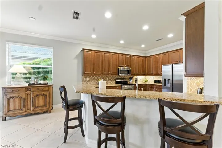 KITCHEN IS OPEN TO ENTERTAIN AND HAS STAINLESS APPLIANCES, BAR AREA WITH PLENTY OF ROOM FOR EXTRA SEATING
