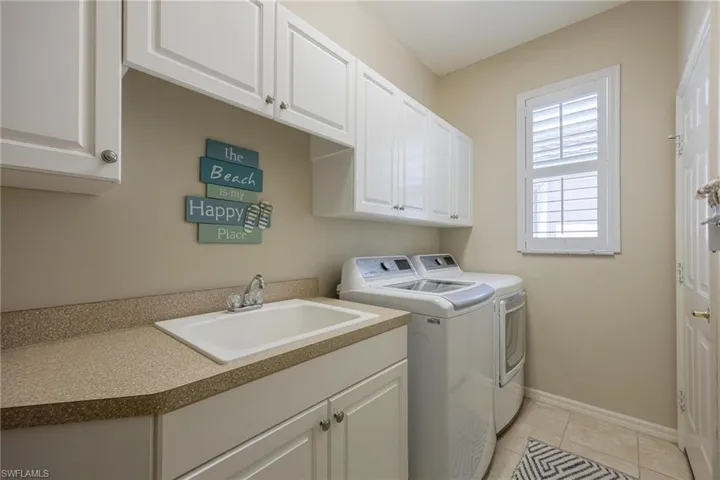In house laundry room with built in cabinets, sink, and folding counter