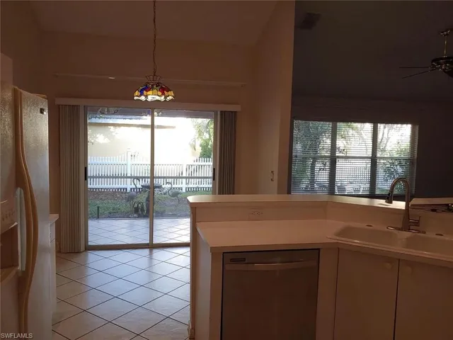 Kitchen featuring dishwasher, light countertops, freestanding refrigerator, healthy amount of natural light, and lofted ceiling