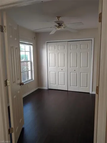 Unfurnished bedroom with dark wood-type flooring, a closet, and a ceiling fan