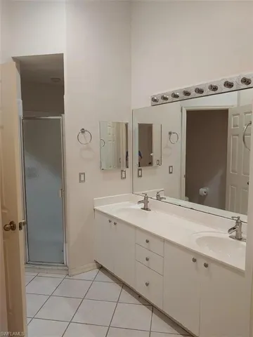 Bathroom with double vanity, a stall shower, and light tile patterned floors