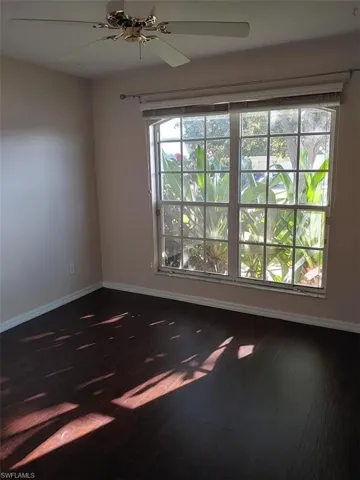 Unfurnished room with a ceiling fan and dark wood-style flooring