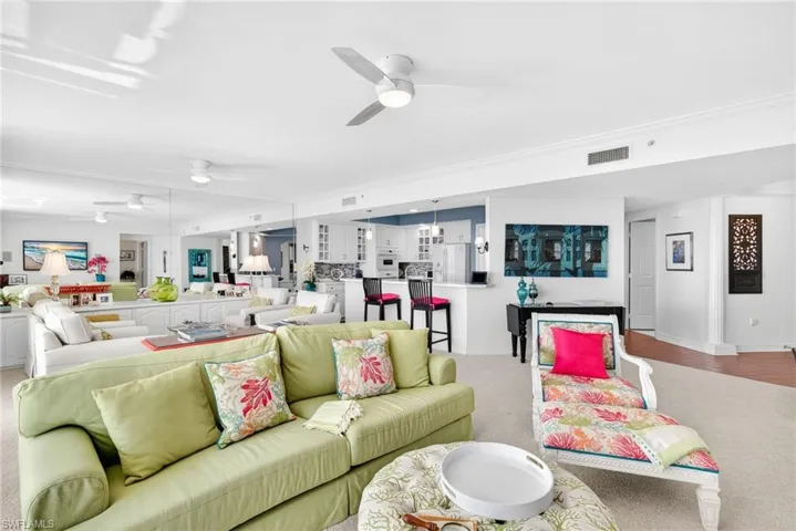 Carpeted living room featuring ceiling fan and baseboards