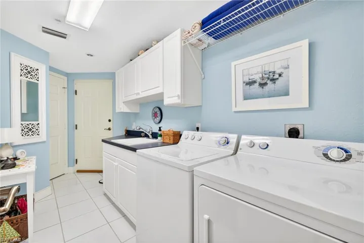Washroom with light tile patterned floors, cabinet space, and washing machine and clothes dryer