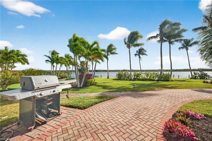 View of patio with area for grilling and a water view
