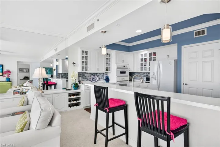 Kitchen with ornamental molding, glass insert cabinets, decorative light fixtures, open floor plan, and white appliances