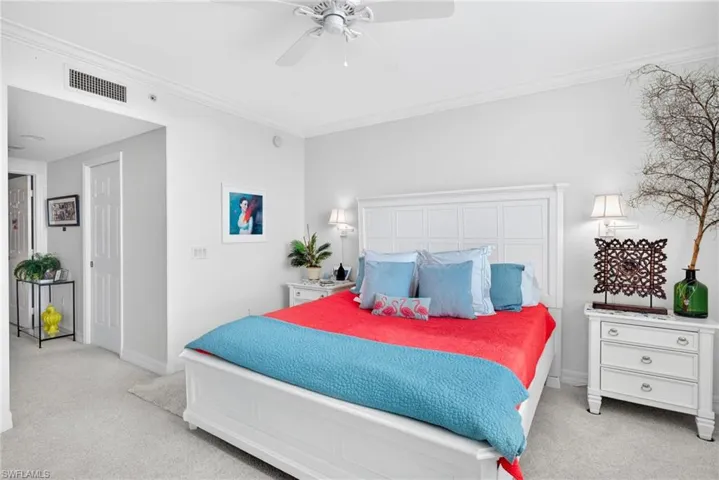 Bedroom with a ceiling fan, light carpet, and crown molding