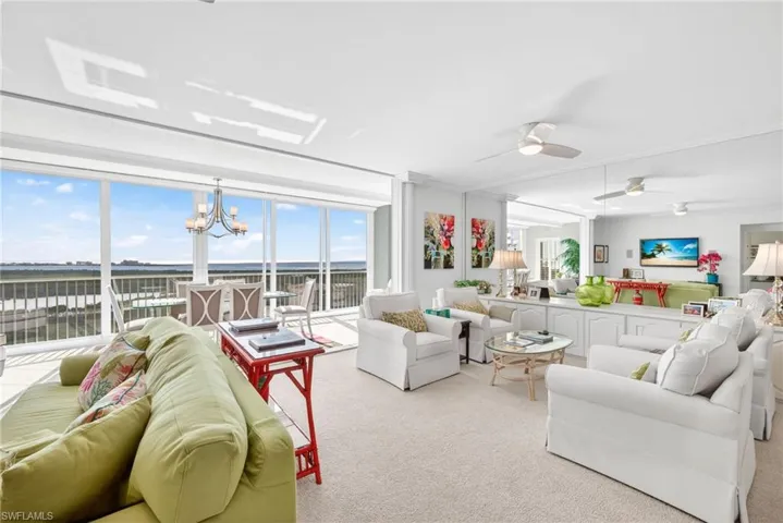 Carpeted living area with plenty of natural light, a chandelier, and ceiling fan