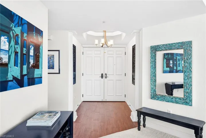 Entryway featuring wood finished floors, a chandelier, and a tray ceiling