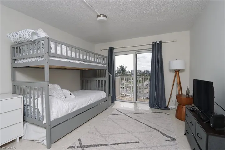 Tiled bedroom with a textured ceiling and access to exterior