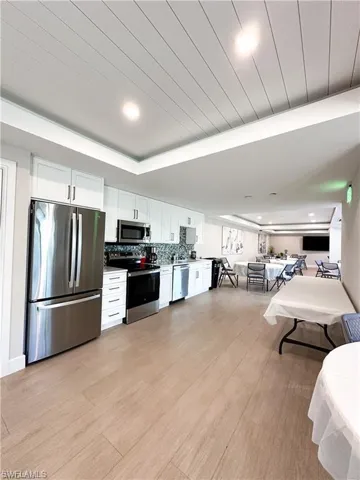 Kitchen featuring appliances with stainless steel finishes, white cabinets, light wood finished floors, tasteful backsplash, and recessed lighting