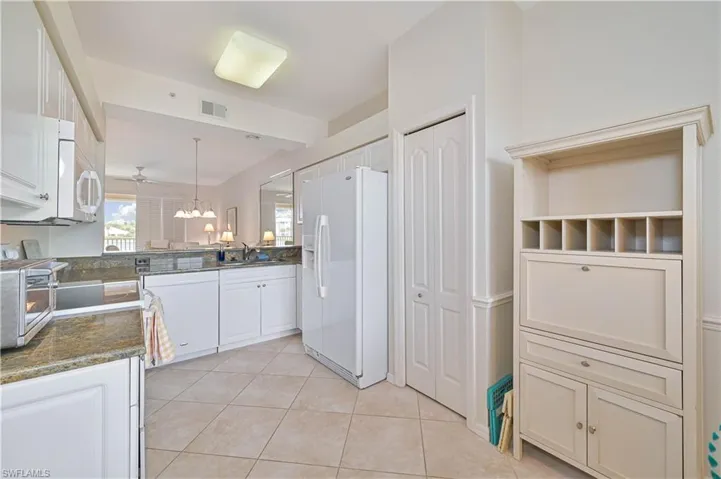 Bright kitchen featuring white cabinetry, a refrigerator, and a built-in microwave
