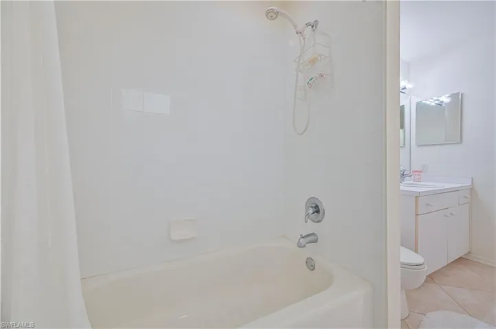 Bathroom featuring a white bathtub with chrome fixtures, white subway tile surround, and a handheld showerhead