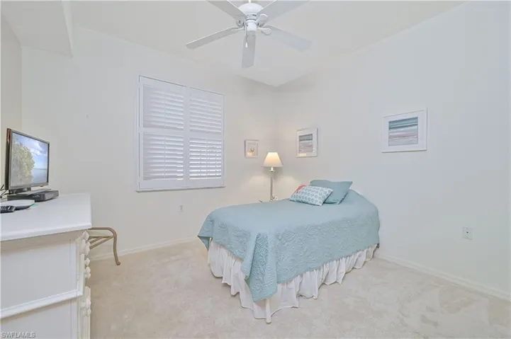 Bright room featuring a window with plantation shutters, a ceiling fan, light-colored walls, and carpeting