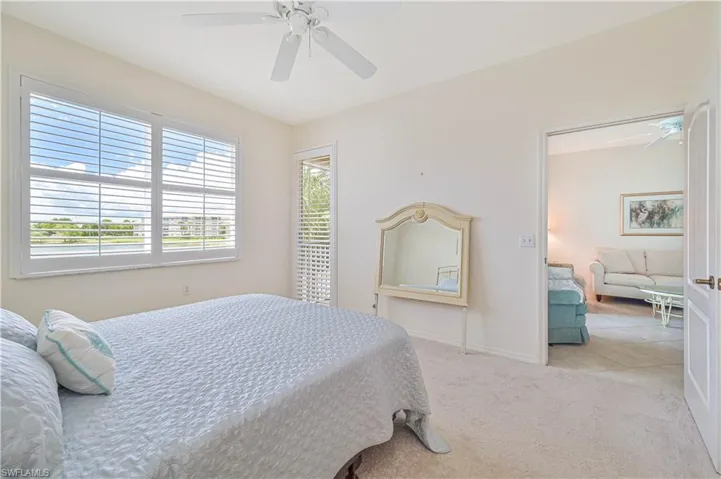 Bright interior space featuring a double window with plantation shutters, ceiling fan, and light-toned carpeting