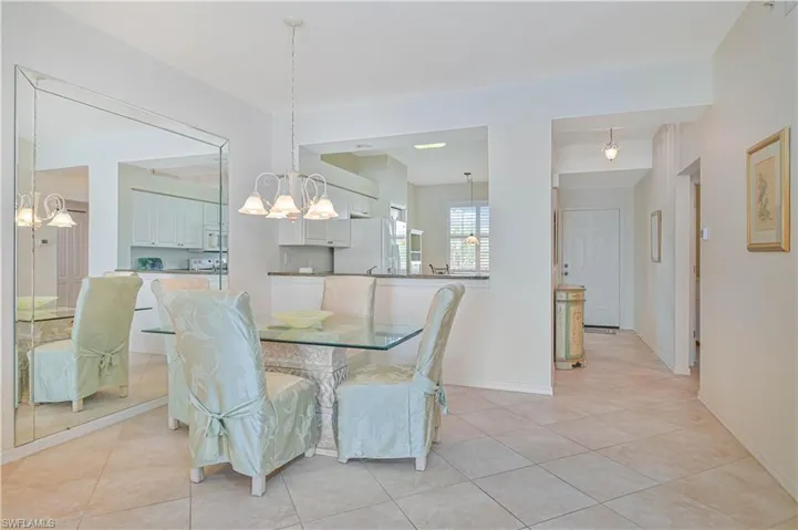 Dining area featuring tiled flooring, a decorative chandelier, and a large mirrored accent wall