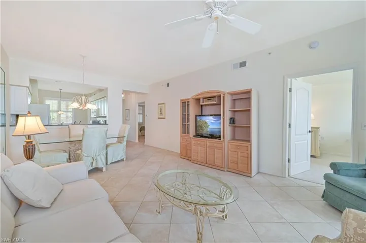 Open-concept living area featuring tile flooring, a ceiling fan, and a light-toned wood-finish entertainment center