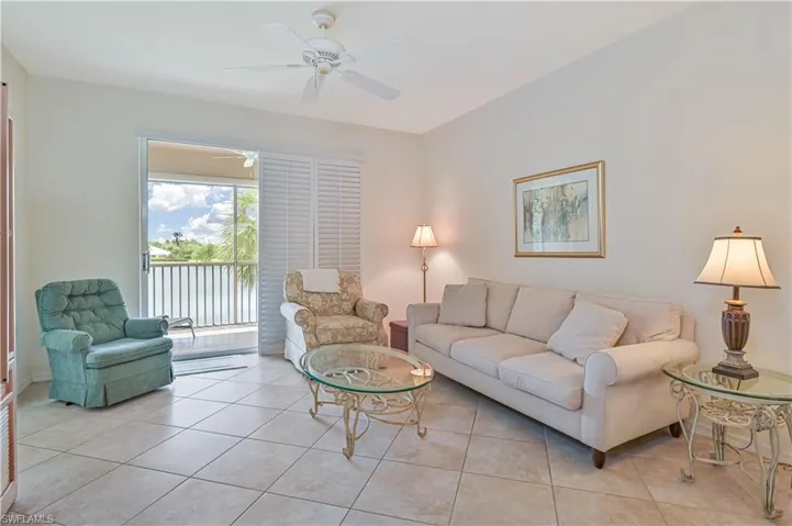 Spacious living area featuring tile flooring, a ceiling fan, and a sliding glass door opening to a private balcony with water views