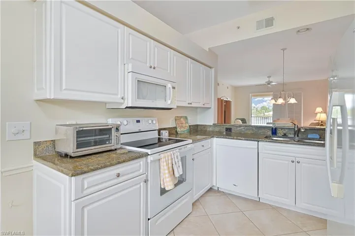 Kitchen featuring white cabinetry, granite countertops, tile flooring, and a stainless steel sink with a high-arc faucet