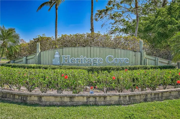 Heritage Cove community signage with a lighthouse motif, set against lush landscaping and a clear sky