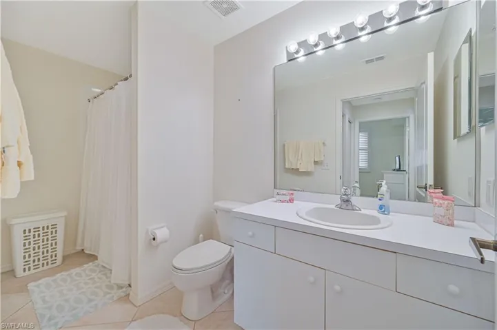 Bathroom featuring a vanity with an integrated sink, a large mirror, and a multi-bulb light fixture