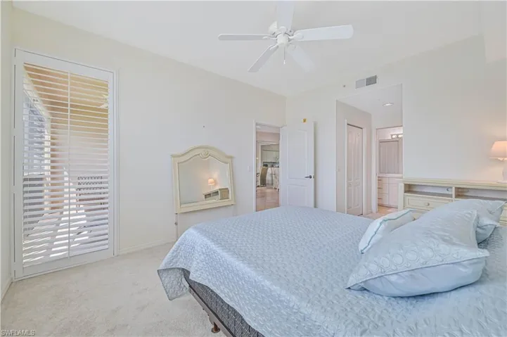 Bedroom featuring neutral wall colors, carpet flooring, a ceiling fan, and French doors with privacy shutters