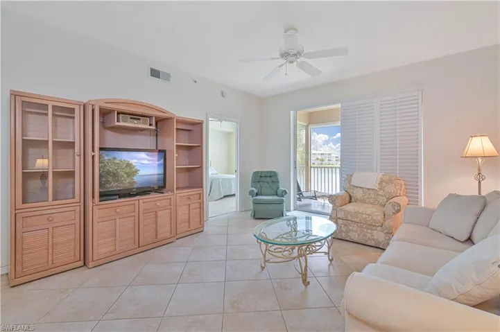 Bright living area featuring neutral tile flooring, a ceiling fan, and a sliding glass door opening to a private balcony