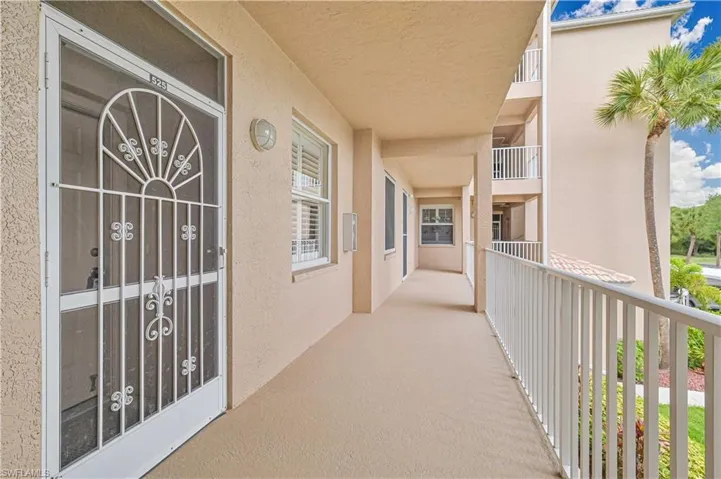 Entryway featuring a decorative security screen door, stucco exterior, and a private balcony with white railings